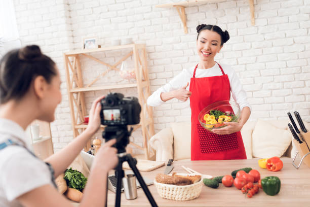 istock Two culinary bloggers mixing diced peppers with salad to camera. 1285269197