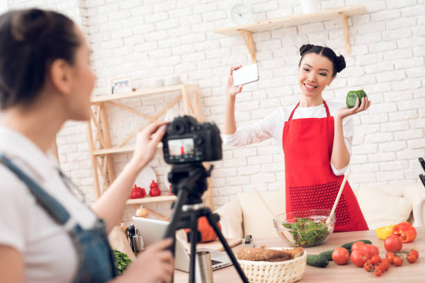 istock Two culinary bloggers taking selfie with one girl behind camera. 1285269212