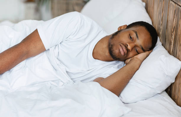 istock Depressed Black Guy Lying Having Insomnia In Bedroom At Home 1285270152