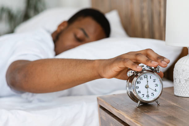 istock Sleepy Black Man Turning Off Alarm Clock Lying In Bed 1285270387