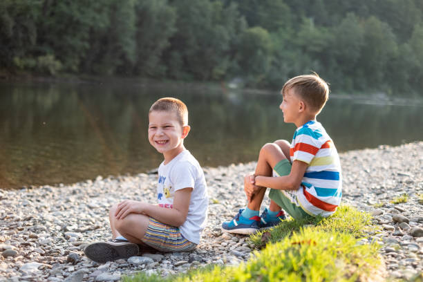istock Two boys sitting on riverbank 1285270390