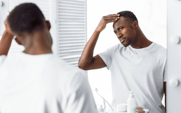 istock Black Guy Examining His Head Searching Gray Hair In Bathroom 1285272142