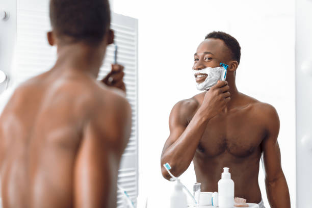 istock Shirtless African American Man Shaving Face Using Razor In Bathroom 1285272241