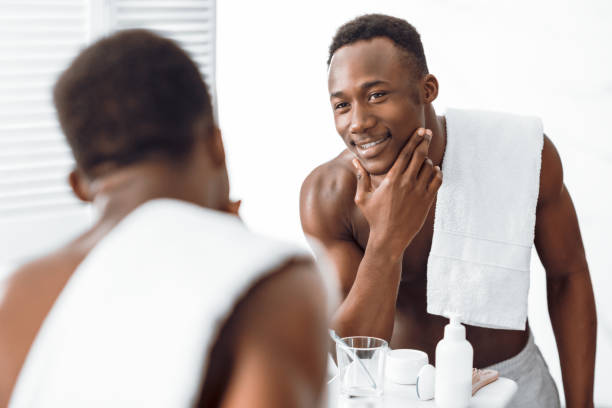 istock Black Guy Touching Well-Shaved Face Caring For Skin In Bathroom 1285273711