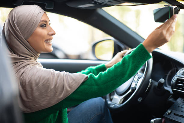 istock Young muslim woman driving alone adjusting rearview mirror 1285273763
