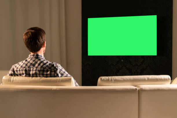 istock A man watches TV with a green screen while sitting on the couch 1285276090