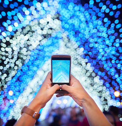 Close-up of woman hands taking pictures of Christmas decoration outdoors in the city with her mobile phone