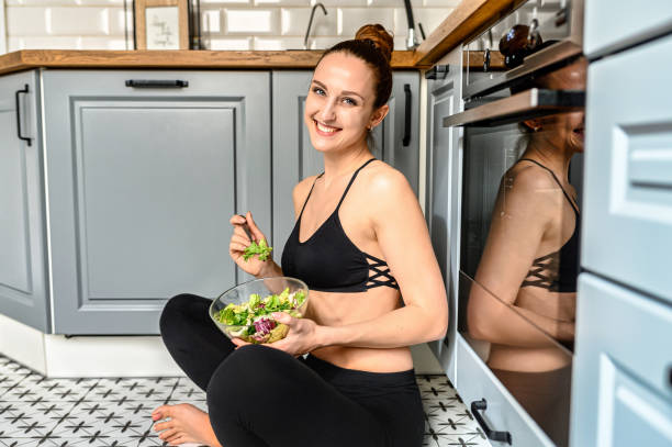 istock Young woman eats salat in the kitchen 1285281539