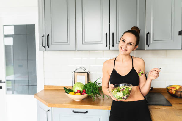 istock Young woman eats salat in the kitchen 1285281548