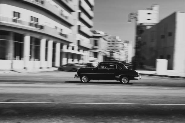Bangkok, Thailand - June 13, 2016: Capture of gray VW Beetle oldtimer in traffic scene near Wanghin Road in late afternoon sun. Inside are two young thai men. In street is queued traffic. Some people are walking in street or are driving motorcycle.
