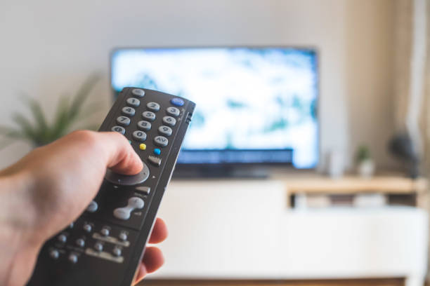 istock Male hand is holding TV remote control, streaming on a smart TV. 1285285939