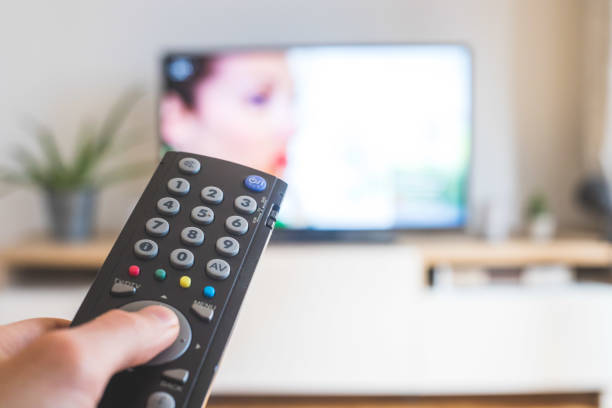 istock Male hand is holding TV remote control, streaming on a smart TV. 1285286083
