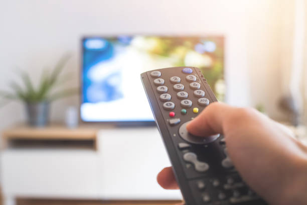 istock Male hand is holding TV remote control, streaming on a smart TV. 1285286170