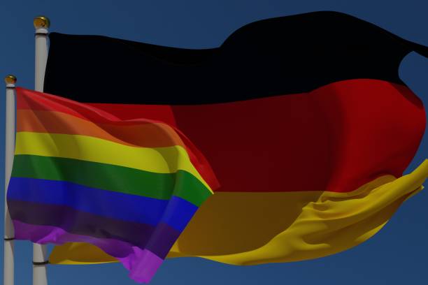LGBT flag and German flag on a pole waving in the wind together representing rights and pride.