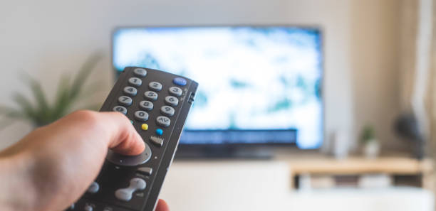 istock Male hand is holding TV remote control, streaming on a smart TV. 1285286241