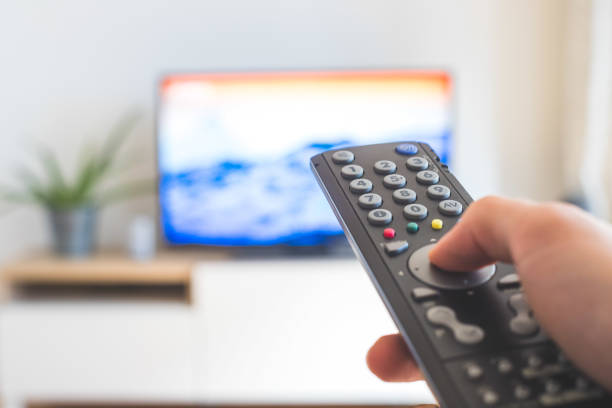 istock Male hand is holding TV remote control, streaming on a smart TV. 1285286482