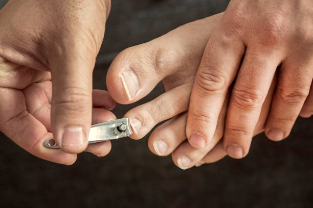 istock hand manicure with nail clipper. self-cutting nails. close up over black background. close-up nail cutting 1285287997