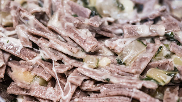 very close up of the succulent and typical italian dish pizzoccheri in a white plate on a table. typical dish from valtellina, lombardy, italy. - pizzoccheri homemade tagliatelle italy imagens e fotografias de stock