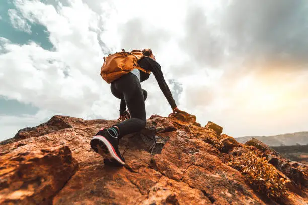 Vector illustration of Erfolgs-Frauenwandererwandern auf Sonnenaufgang - Junge Frau mit Rucksack steigt auf den Berggipfel. Discovery Travel Destination Konzept
