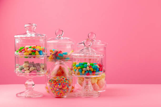 istock Glass containers with candies against pink background 1285301239