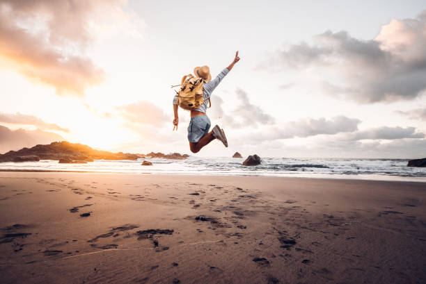 istock Happy man jumping at the beach on a sunset background 1285301669