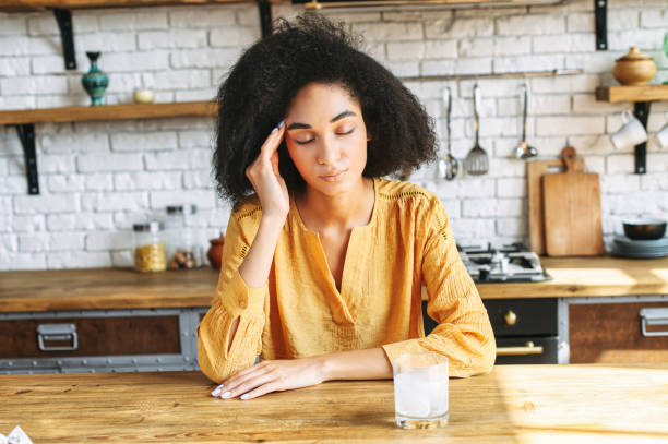 istock Afro-American girl sits at the table with a headache 1285301837