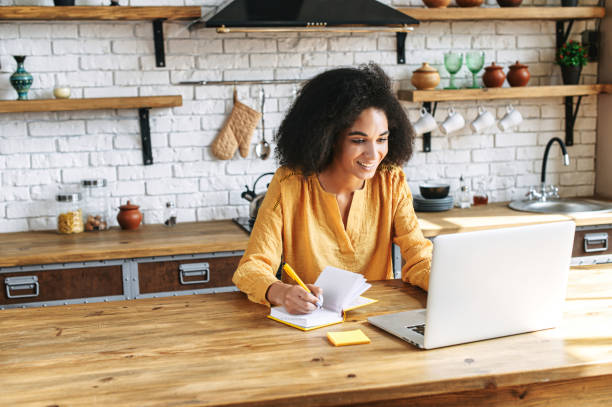 istock Beautiful afro girl writes in notebook from laptop 1285301943