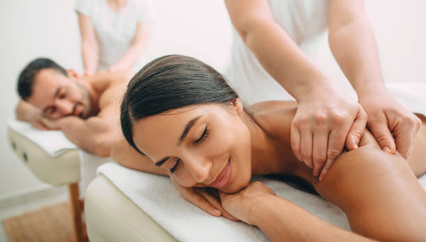 bella coppia ottenere un massaggio alla schiena, centro benessere fine settimana per coppia. bella donna di razza mista e l'uomo si rilassa mentre il massaggio alla schiena - spa treatment health spa massaging couple foto e immagini stock