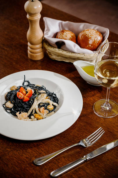 istock Black spaghetti. Spicy Black seafood pasta with squid with basil on wooden table. 1285307142