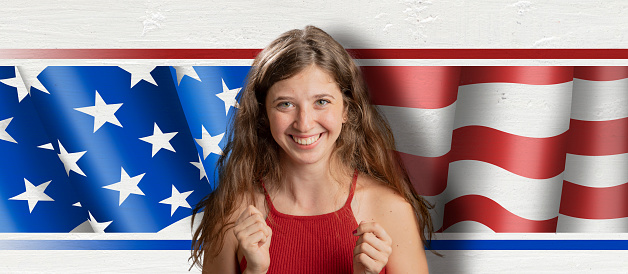 Young beautiful woman celebrating in front of american flag