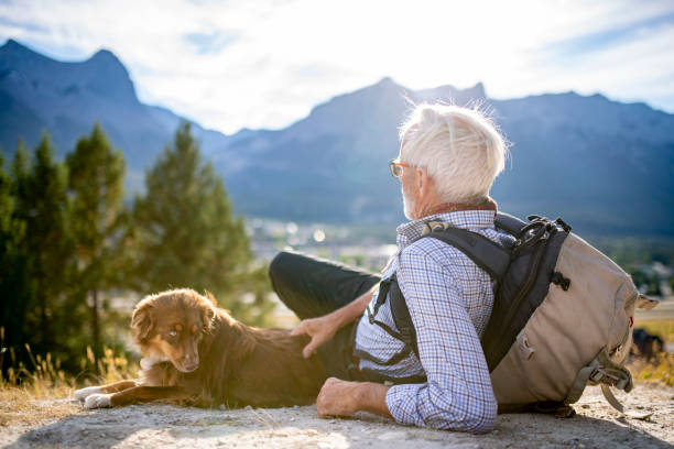 istock Senior man sits with a dog on a leash in the mountains 1285308933