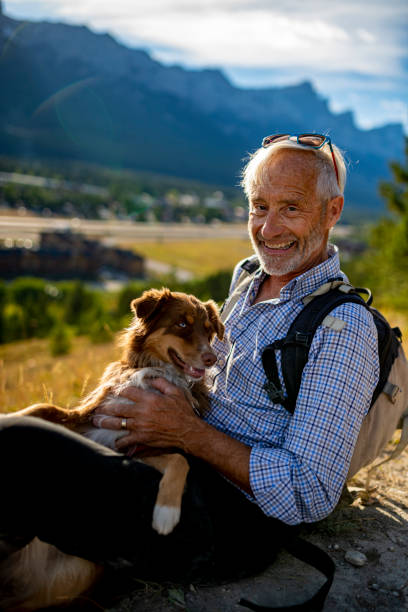 istock Senior man sits with a dog on a leash in the mountains 1285308944