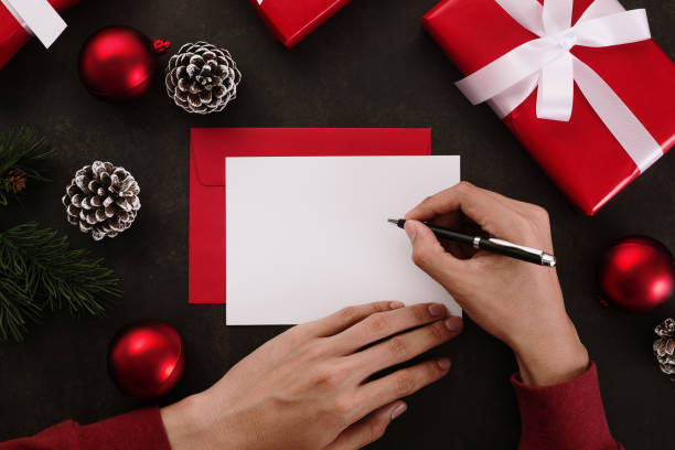 istock Hands writing white greeting card mockup with christmas decoration on grunge background 1285309993