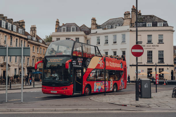 Bath, United Kingdom - June 28, 2015: The Abbey Church of Saint Peter and Saint Paul, also known as Bath Abbey in Bath, Somerset, England, United Kingdom. It is an Anglican parish church and a former Benedictine monastery that was founded in the 7th century. Town square, tour bus, tourists and blue sky with clouds are in the image. 