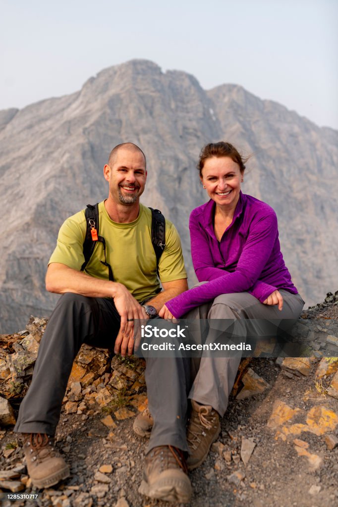Couple enjoy time on the top of a mountain Mountains layers in the distance Couple - Relationship Stock Photo
