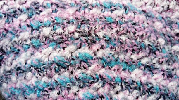 istock Knitting with synthetic threads using the thread technique. Close-up of a knitted warm winter product - hats, sweaters, mittens. Closeup of pink, white, black, green and blue yarn 1285311604