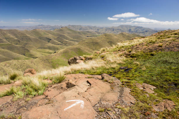 Drakensberg hike View over the Free State Drakensberg Mountains, South Africa, on a clear sunny day, with arrow painted in the foreground indicating the direction of a hiking trail. golden gate highlands national park stock pictures, royalty-free photos & images