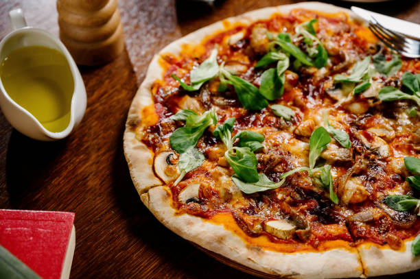 istock Mushroom pizza with addition mozzarella cheese and herbs on a wooden table, top view 1285313216