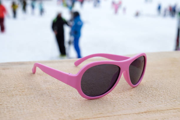 pink-rimmed sunglasses on wooden slope in apres ski bar or cafe, with ski slope in background. concept of winter sports, leisure, recreation, relaxation in resort. horizontal - apres ski winter friendship ski imagens e fotografias de stock