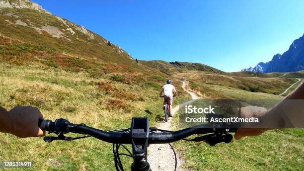 Pov Perspective View Of Ebiking Along Mountain Slope Behind A Young Woman Mountain Biking Stock Photo - Download Image Now