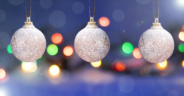 istock Three baubles with glitter are hanging against the blurred Christmas lights 1285315128