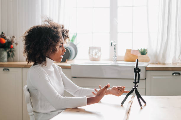 istock Young blogger sitting at table against smartphone on tripod 1285315408