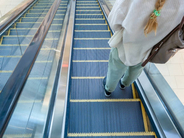 istock Escalator going down with a girl standing on it in jeans and a shirt 1285316056
