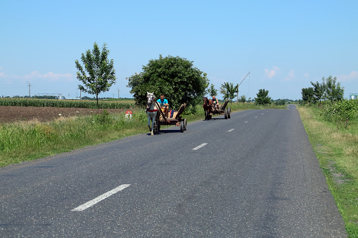 Ion Corvin/Romania; 07/06/2018. Old horse carriages driving along the side of the road.