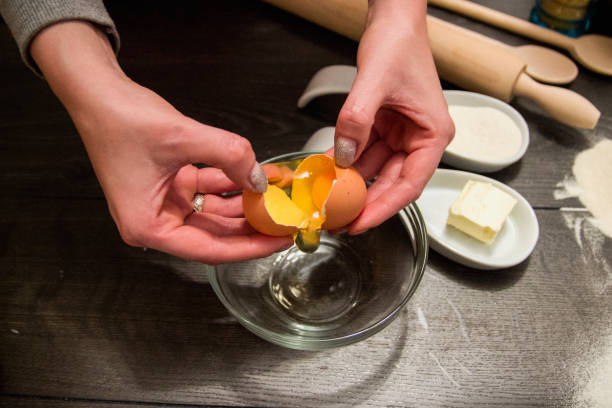 istock Closeup of a pair of hands cracking an egg into a glass bowl 1285318155