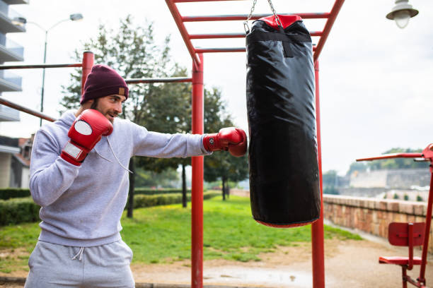 entraînement lourd de sac à l’extérieur - men sweat combative sport boxing photos et images de collection