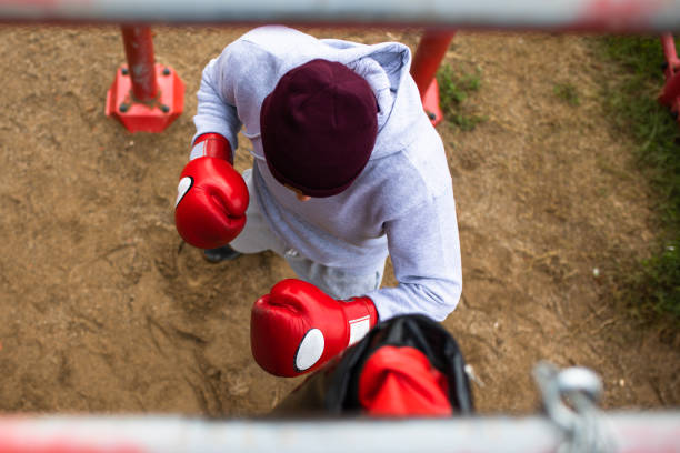 un entraînement de boxeur avec un sac de poinçonnage lourd - men sweat combative sport boxing photos et images de collection