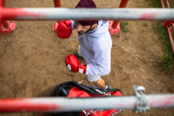 un boxeur contre son sac de poinçonnage - men sweat combative sport boxing photos et images de collection