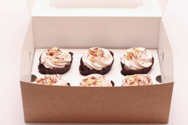 istock Delicious chocolate cupcakes with cream in an open gift box on a white background 1285320178