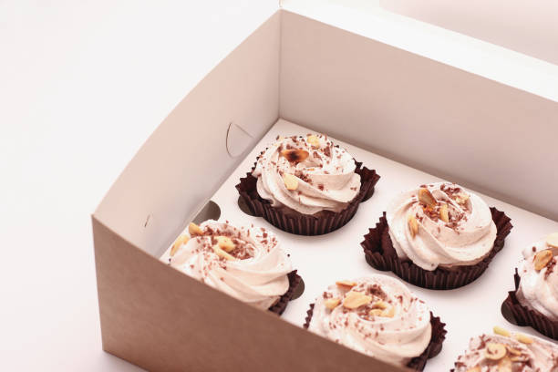 istock Delicious chocolate cupcakes with cream in an open gift box on a white background partial photo 1285320180